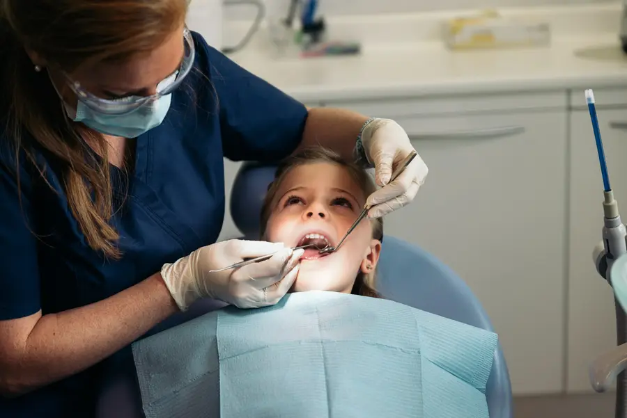 Criança durante consulta odontológica de rotina com a dentista.